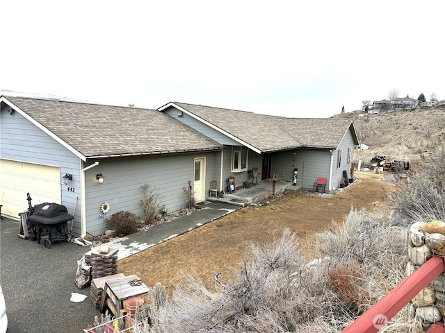 single story home with a garage and a shingled roof