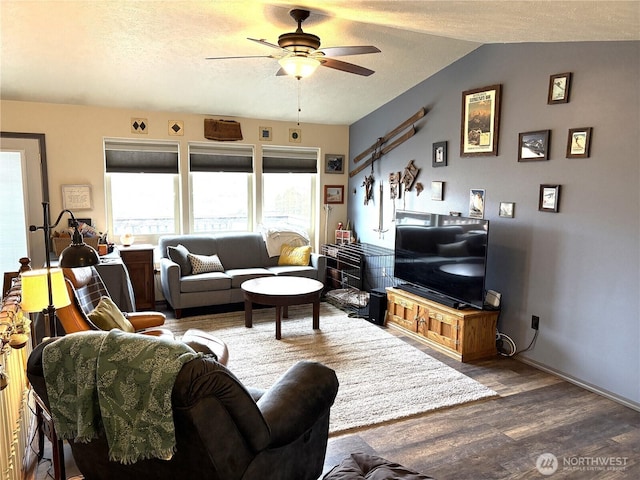 living room featuring a textured ceiling, a ceiling fan, vaulted ceiling, and wood finished floors