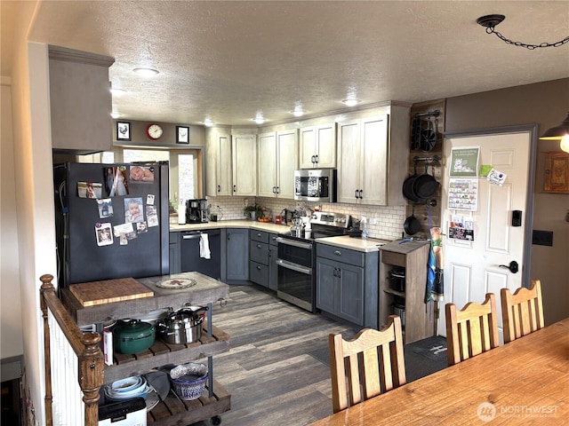 kitchen featuring stainless steel appliances, light countertops, backsplash, and gray cabinetry