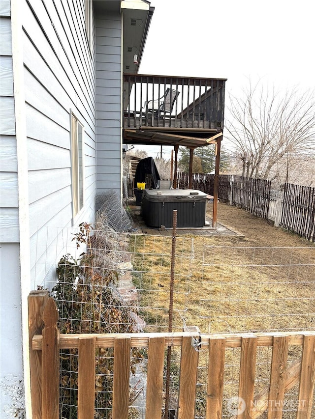 wooden deck with a hot tub and a fenced backyard