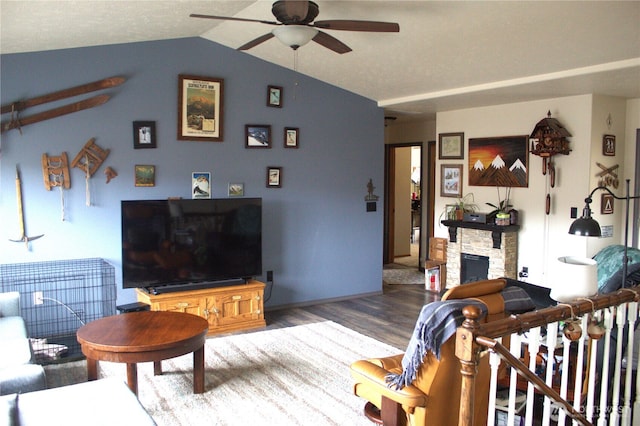 living room featuring vaulted ceiling, a fireplace, ceiling fan, and wood finished floors