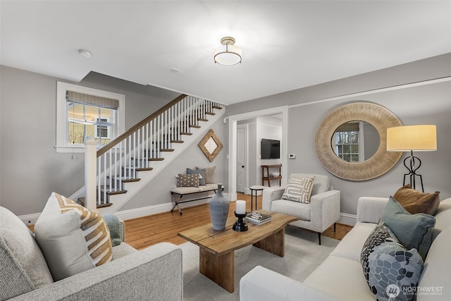 living room with baseboards, stairway, and light wood-style floors