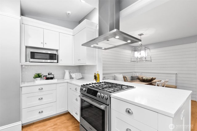 kitchen with stainless steel appliances, light countertops, white cabinets, and island range hood