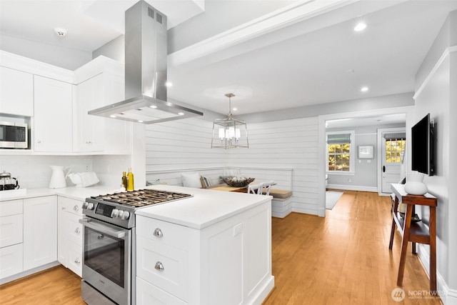 kitchen featuring white cabinets, island exhaust hood, stainless steel appliances, and light countertops