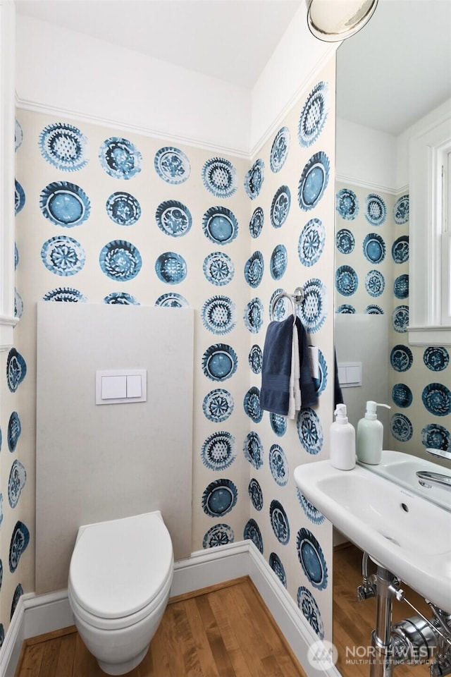 half bathroom featuring toilet, baseboards, and wood finished floors