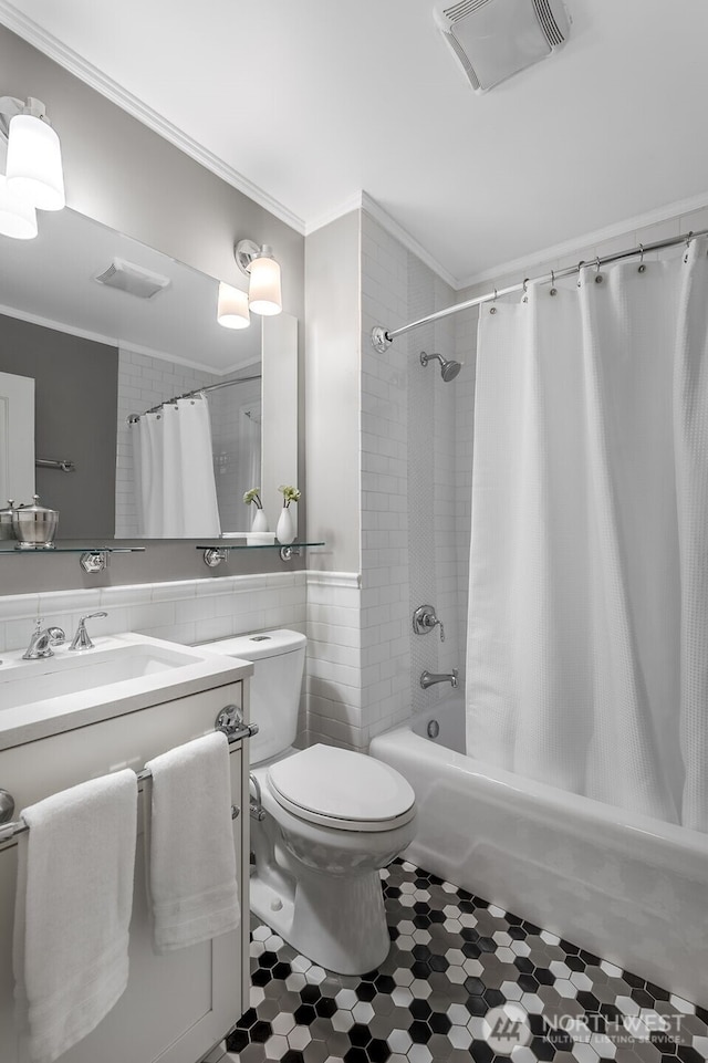 bathroom featuring visible vents, toilet, ornamental molding, vanity, and tile walls