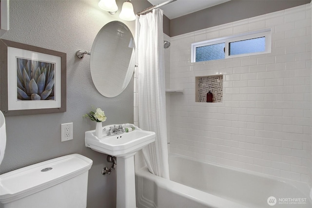 full bathroom with shower / tub combo, a textured wall, and toilet