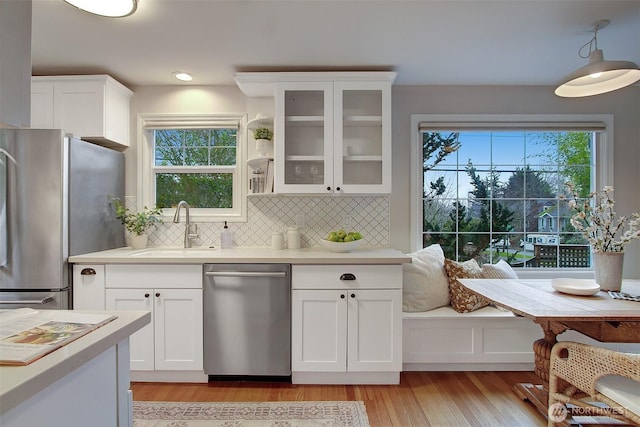 kitchen with stainless steel appliances, white cabinets, light countertops, and glass insert cabinets