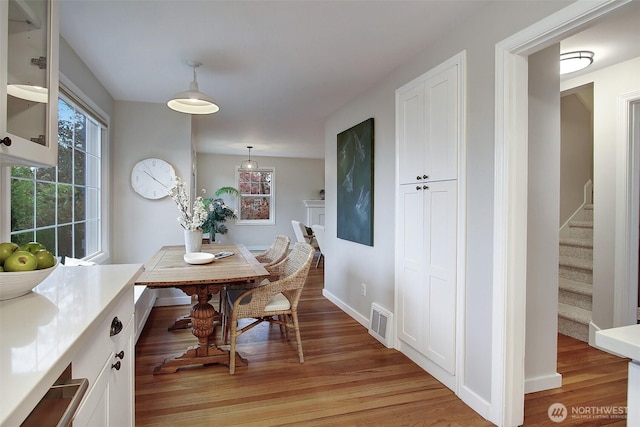 dining space featuring stairs, light wood finished floors, visible vents, and baseboards