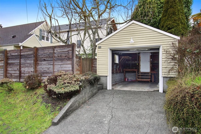 detached garage featuring driveway and fence