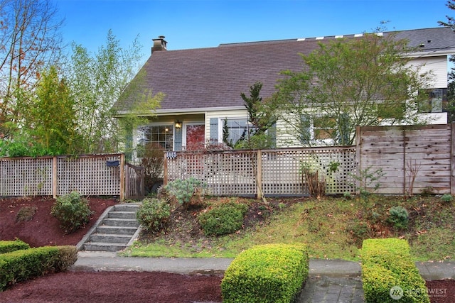 view of front of home featuring stairs, a chimney, and fence