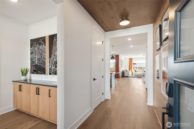 corridor featuring baseboards, wood finished floors, and recessed lighting