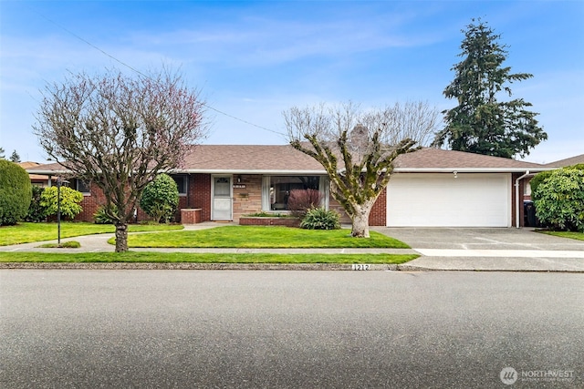 ranch-style house featuring concrete driveway, a front yard, a shingled roof, a garage, and brick siding