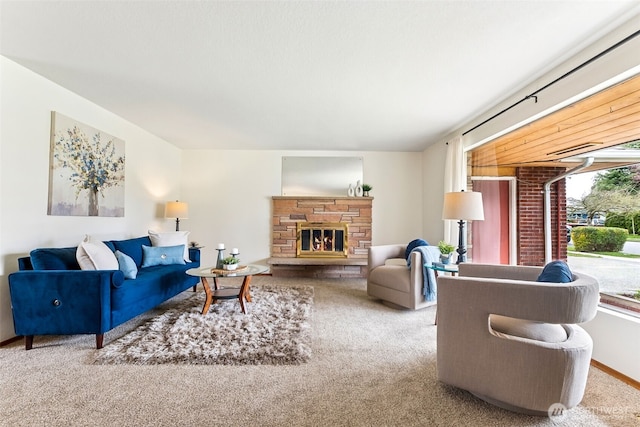 carpeted living room featuring a stone fireplace