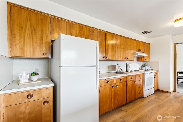 kitchen featuring visible vents, under cabinet range hood, white appliances, light wood finished floors, and light countertops