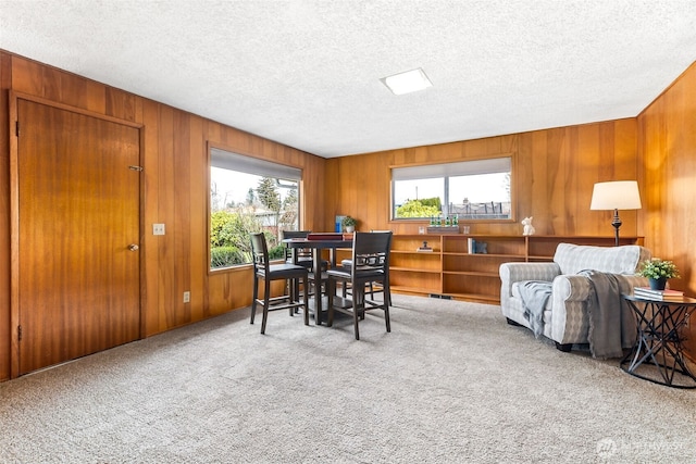 dining room with carpet floors, a textured ceiling, and wooden walls