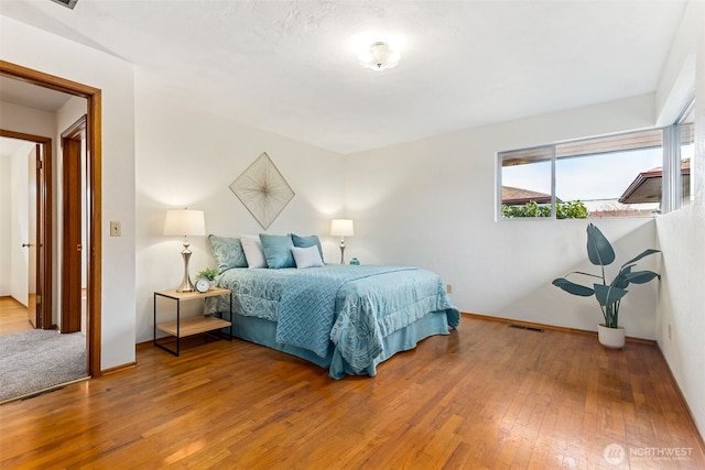 bedroom with baseboards, visible vents, and wood-type flooring