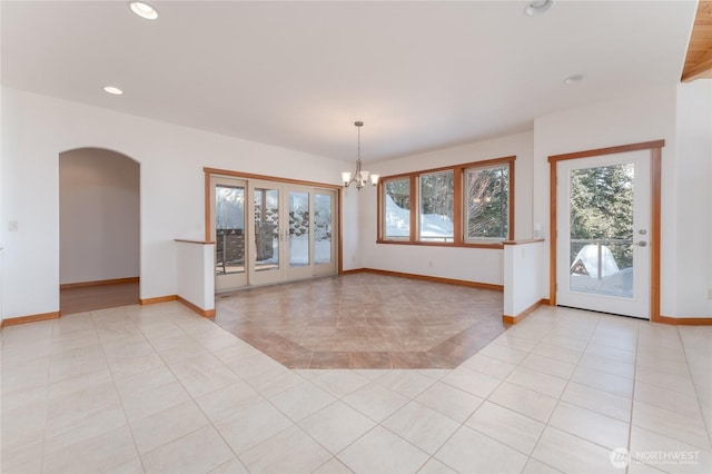 empty room with light tile patterned floors, baseboards, arched walkways, and recessed lighting