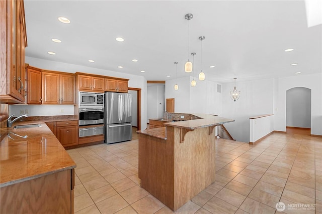 6760 Forest Ridge Dr, Wenatchee, WA 98801 - kitchen with appliances with stainless steel finishes, a warming drawer, light tile patterned flooring, arched walkways, and a breakfast bar