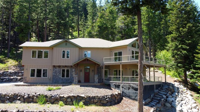 6760 Forest Ridge Dr, Wenatchee, WA 98801 - view of front of house with stone siding, a balcony, board and batten siding, and a view of trees
