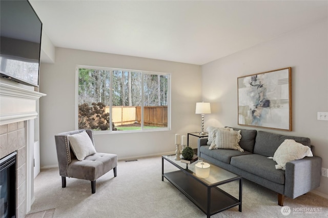 living room with a tiled fireplace, carpet flooring, visible vents, and baseboards