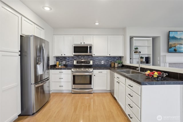 kitchen with stainless steel appliances, white cabinets, a sink, and a peninsula