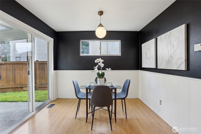 dining space with a wealth of natural light, wainscoting, visible vents, and wood finished floors