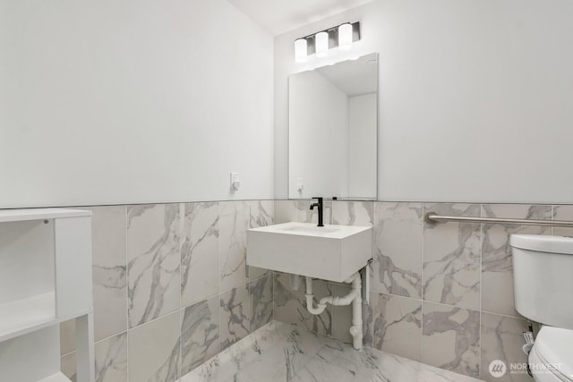 bathroom with a wainscoted wall, toilet, and tile walls