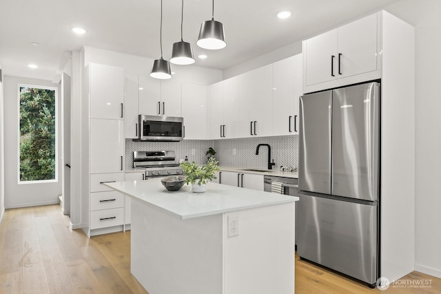 kitchen featuring appliances with stainless steel finishes, a center island, light countertops, and white cabinetry