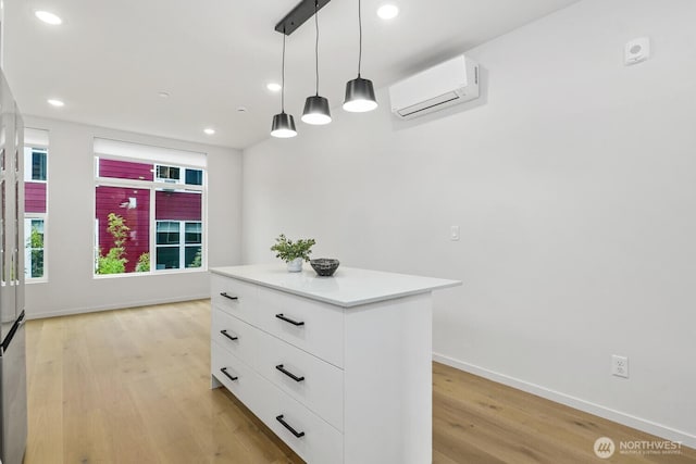 kitchen featuring white cabinets, light countertops, a wall mounted AC, a center island, and decorative light fixtures