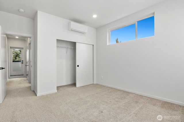 unfurnished bedroom featuring a closet, an AC wall unit, light carpet, and baseboards