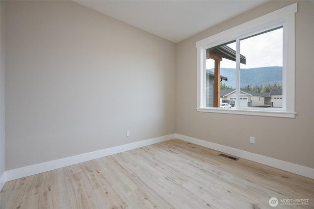 empty room with baseboards, wood finished floors, and visible vents