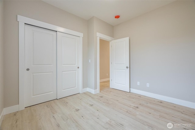 unfurnished bedroom with baseboards, wood finished floors, and a closet