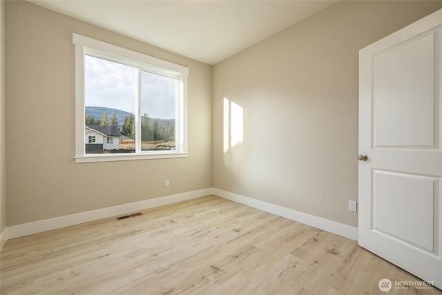 spare room featuring baseboards, wood finished floors, and visible vents