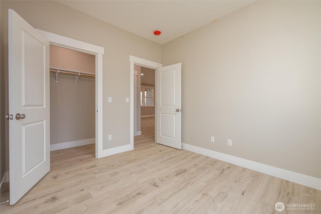 unfurnished bedroom with wood finished floors, a closet, and baseboards