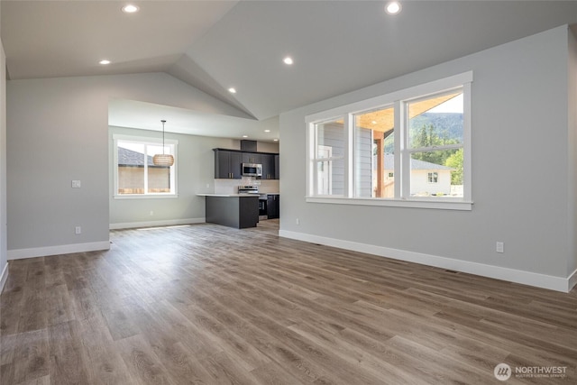 6511 Watson Loop, Maple Falls, WA 98266 - unfurnished living room featuring wood finished floors, lofted ceiling, baseboards, and recessed lighting