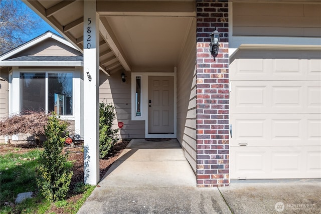 property entrance with a garage and brick siding