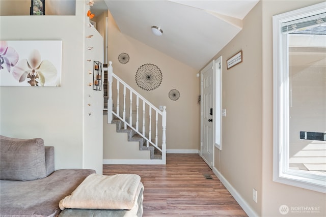 entryway featuring visible vents, wood finished floors, stairway, baseboards, and lofted ceiling