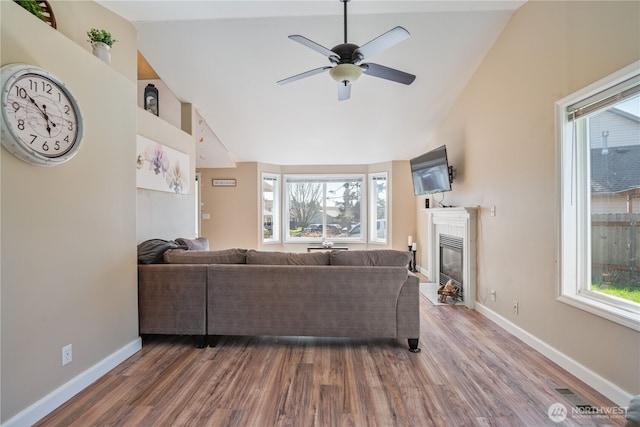 living room with plenty of natural light, a glass covered fireplace, and wood finished floors