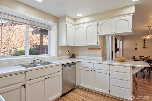 kitchen featuring light wood-type flooring, a sink, stainless steel dishwasher, white cabinetry, and a peninsula