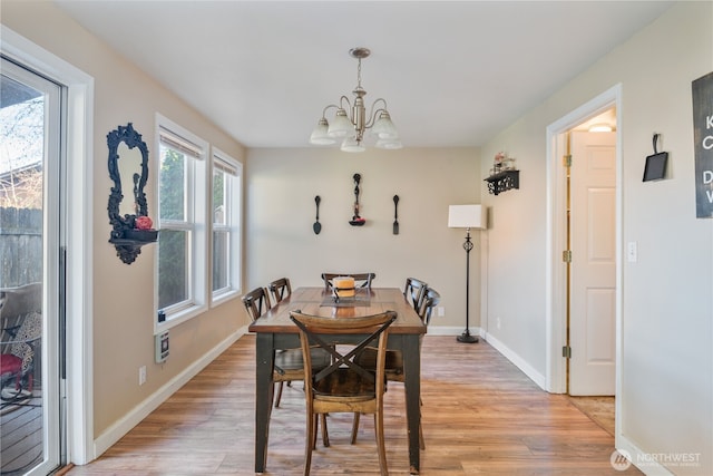 dining room with baseboards, a chandelier, and light wood finished floors