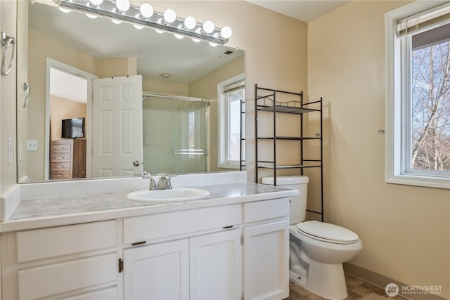 full bath with a shower stall, toilet, vanity, and baseboards