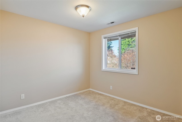 carpeted empty room featuring baseboards and visible vents