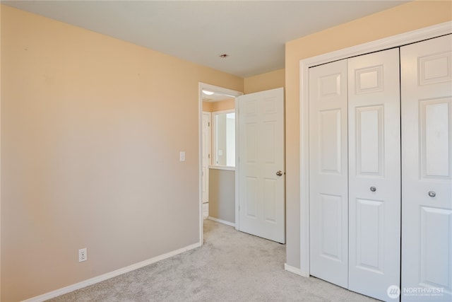 unfurnished bedroom featuring a closet, baseboards, and light colored carpet