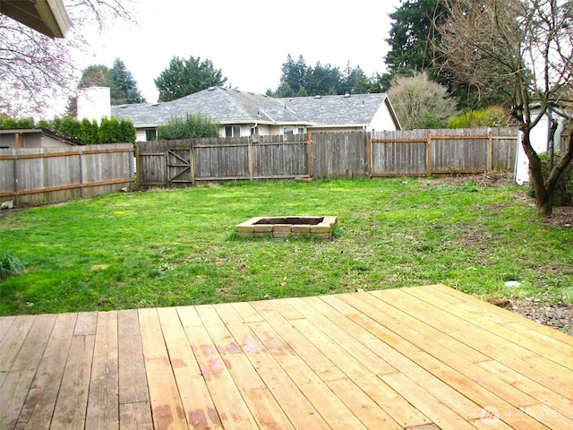 wooden terrace with a yard, a fire pit, and a fenced backyard