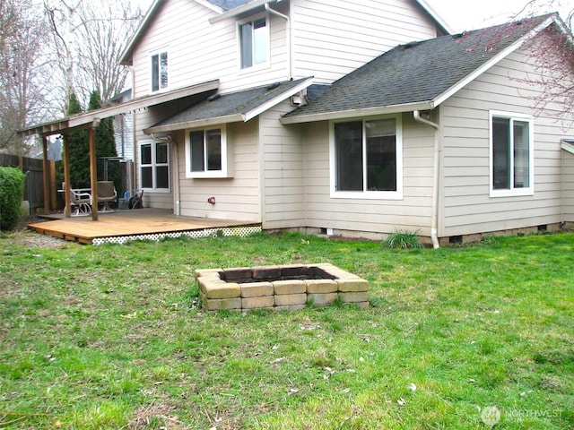 back of property featuring a deck, a yard, roof with shingles, and an outdoor fire pit