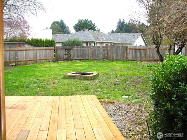 view of yard featuring a wooden deck, a fenced backyard, and an outdoor fire pit