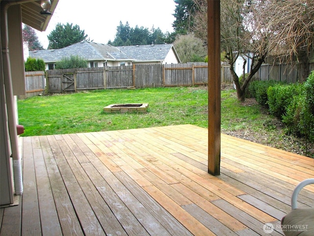 wooden deck featuring a lawn, an outdoor fire pit, and a fenced backyard