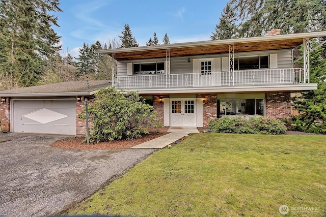 view of property with aphalt driveway, a front lawn, brick siding, and a balcony