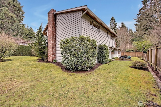 view of home's exterior featuring a patio area, a lawn, a chimney, and a fenced backyard